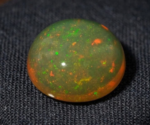 Natural Brazilian opal gemstone on dark textured fabric