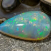Natural pear shaped Brazilian opal gemstone on antique textured surface