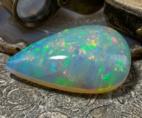 Natural pear shaped Brazilian opal gemstone on antique textured surface