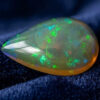 Natural pear shaped Brazilian opal gemstone on deep blue velvet fabric