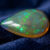 Natural pear shaped Brazilian opal gemstone on deep blue velvet fabric
