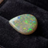 Natural pear shaped Brazilian opal gemstone on black velvet jewelry display