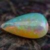 Natural pear shaped Brazilian opal gemstone on rustic wooden surface