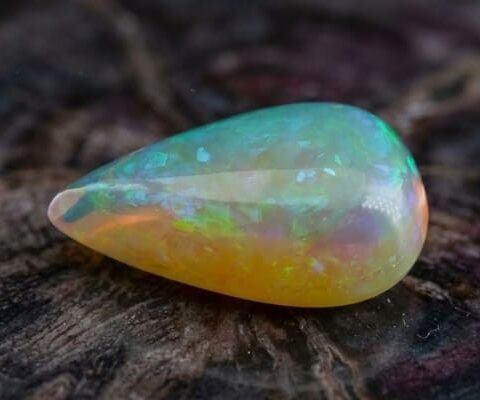 Natural pear shaped Brazilian opal gemstone on rustic wooden surface