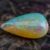 Natural pear shaped Brazilian opal gemstone on rustic wooden surface