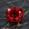 Natural cushion cut Burma red spinel gemstone on black marble surface