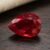 Natural pear shaped Burma ruby gemstone on dark wooden surface