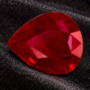 Natural pear shaped Burma ruby gemstone on black textured fabric