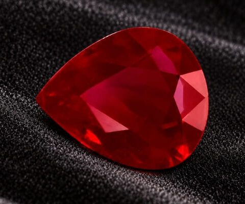 Natural pear shaped Burma ruby gemstone on black textured fabric