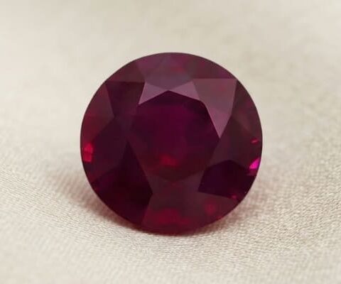 Natural oval Burma ruby with GIA report on soft beige fabric