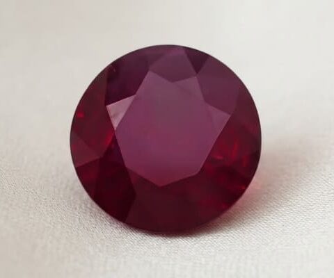 Natural oval Burma ruby with GIA report on soft cream fabric