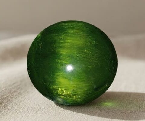 Natural cat’s eye demantoid garnet with GIA report on soft beige fabric