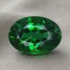 Natural oval chrome tourmaline gemstone on soft grey fabric