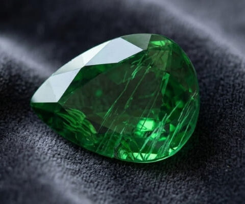 Natural chrome tourmaline gemstone on dark grey fabric