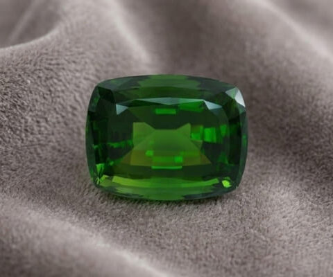 Natural cushion cut chrome tourmaline gemstone on soft grey fabric