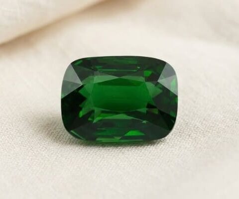 Natural cushion cut chrome tourmaline gemstone on soft cream fabric