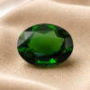 Natural oval chrome tourmaline gemstone on soft beige fabric