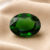 Natural oval chrome tourmaline gemstone on soft beige fabric