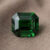 Natural emerald cut chrome tourmaline gemstone on soft brown fabric