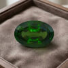 Natural oval chrome tourmaline gemstone on soft brown jewelry display