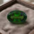 Natural oval chrome tourmaline gemstone on soft brown jewelry display