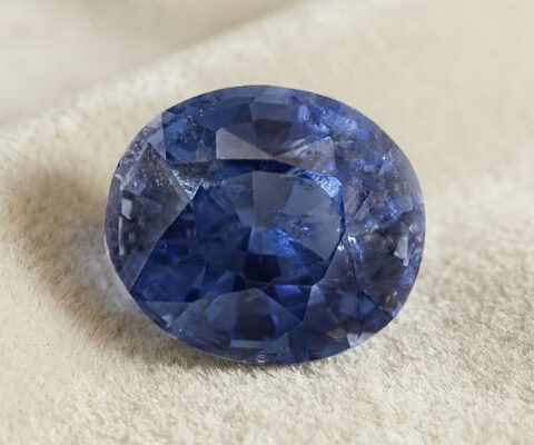 Natural oval cobalt spinel gemstone on soft cream fabric