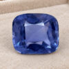 Natural cushion cut cobalt spinel gemstone on soft beige jewelry display