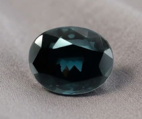 Natural oval color change garnet gemstone on soft grey fabric