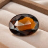 Natural oval tourmaline gemstone on soft beige jewelry display