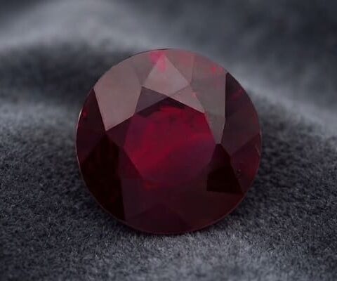 Natural oval East African ruby gemstone on dark grey fabric
