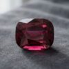 Natural cushion-cut garnet gemstone on dark grey fabric