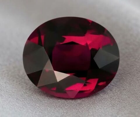 Natural oval garnet gemstone on soft grey fabric