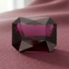 Natural emerald cut garnet gemstone on soft pink fabric