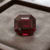 Natural emerald cut garnet gemstone on soft grey jewelry display