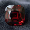 Natural cushion cut garnet gemstone on dark grey fabric