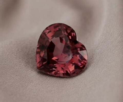 Natural heart shaped garnet gemstone on soft beige fabric