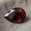 Natural pear shaped rubellite gemstone on soft grey fabric