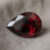 Natural pear shaped rubellite gemstone on soft grey fabric
