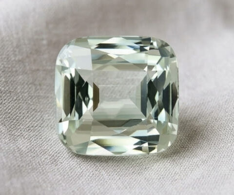 Natural cushion cut green beryl gemstone on soft ivory satin