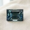 Natural emerald cut green blue sapphire gemstone on soft cream fabric
