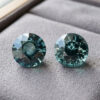 Natural round green blue sapphire pair on soft grey jewelry display