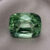 Natural cushion cut green sapphire gemstone on soft grey fabric