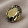 Natural oval green sapphire gemstone on soft taupe fabric