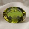 Natural oval green sapphire gemstone on soft cream fabric