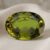 Natural oval green sapphire gemstone on soft cream fabric