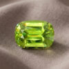 Natural cushion cut green sphene gemstone on soft taupe fabric