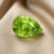 Natural pear shaped green sphene gemstone on soft beige fabric