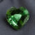 Natural heart shaped green tourmaline gemstone on dark grey fabric
