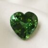 Natural heart shaped green tourmaline gemstone on soft cream fabric