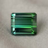 Natural emerald cut green tourmaline gemstone on soft grey fabric